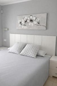 a bedroom with a white bed with a painting on the wall at Apartamento en Olivanova in Casas Devesa