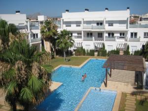 a person in a swimming pool next to a building at Apartamentos Fercamar Denia in Denia