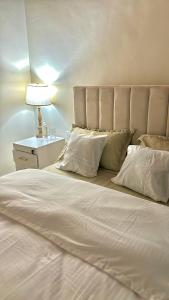 a bedroom with a large white bed with a lamp at Amber Home Kigali in Kigali