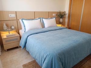 a bed with a blue blanket and two pillows at Jardines del mar III-2ª linea de playa Piscina y Parking Ideal familias Marina d'Or in El Borseral