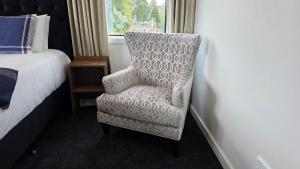 a bedroom with a chair next to a bed and a window at Lake Taupo Hotel in Taupo