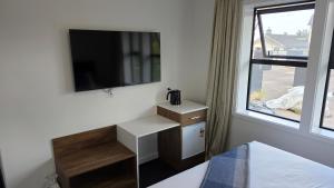 a bedroom with a tv and a desk and a window at Lake Taupo Hotel in Taupo