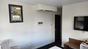 a living room with a white wall and a tv at Lake Taupo Hotel in Taupo