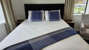 a bed with blue and white pillows and a window at Lake Taupo Hotel in Taupo