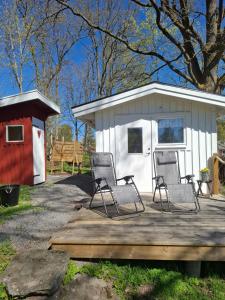 a group of chairs sitting on a deck next to a shed at Gäststugan in Alingsås