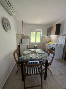 a kitchen with a table and chairs and a clock at Apartman LUCIJA, dostupan minimum 7 NOCENJA i VISE, AVAIBLE FOR RENT MINIM 7 NIGHTS AND MORE in Sutomore