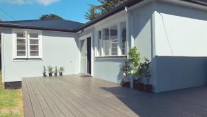 a house with a wooden deck in front of it at Sun kissed beach haven in Waitarere