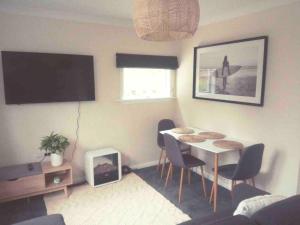 a living room with a table and chairs and a tv at Sun kissed beach haven in Waitarere