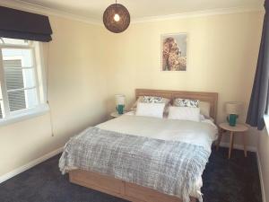 a bedroom with a bed and two tables and a window at Sun kissed beach haven in Waitarere