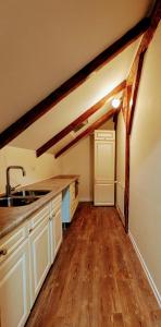 a kitchen with white cabinets and a sink and wooden floors at Karakul Shepherd House in Tinglev