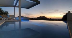 a swimming pool with chairs and a sunset in the background at La Panache Guesthouse in Gros Islet