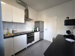 a kitchen with white cabinets and a black counter top at FEWO Leonie 3 Schlafzimmer Apartment in Hückeswagen