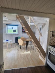 a kitchen and living room with a wooden staircase in a tiny house at Hyttan in Åkirkeby +13 photos