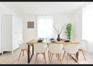a dining room with a wooden table and white chairs at Le sympathique in Ittenheim