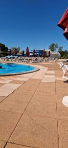 a swimming pool with lounge chairs and an umbrella at Maisonnette duplex 4 pers proche mer et golf in Talmont