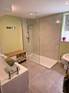 a bathroom with a shower and a tub and a sink at Mortimers Farm Barn in Saffron Walden