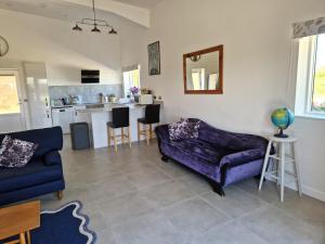 a living room with a purple couch and a kitchen at Mortimers Farm Barn in Saffron Walden
