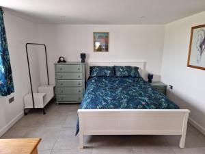 a bedroom with a white bed and a dresser at Mortimers Farm Barn in Saffron Walden