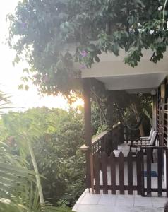 a porch with chairs and a fence and trees at La Panache Guesthouse in Gros Islet