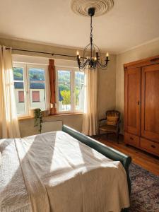 a bedroom with a bed and a chandelier and windows at Das Mosel Ferienhaus in Zell an der Mosel