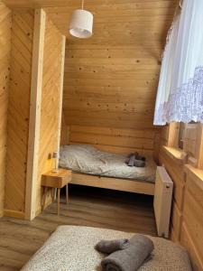 a room with a bed in a wooden cabin at Domek Pod Tatrami - Koniówka, blisko Term Chochołowskich in Koniówka