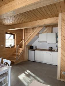 a kitchen with white cabinets in a wooden cabin at Domek Pod Tatrami - Koniówka, blisko Term Chochołowskich in Koniówka