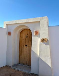 a wooden door in a white wall at Dar Emna in El Guecheïne