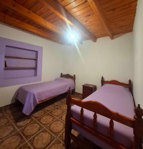 two beds in a room with a wooden ceiling at Hostal Nahiara, Iruya in Iruya