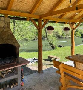 a wooden pavilion with a picnic table and an outdoor oven at River Resort Vinac Jajce in Jajce