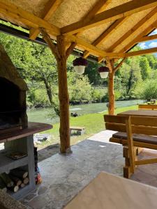 a wooden pergola with a table and a bench at River Resort Vinac Jajce in Jajce