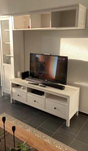 a white entertainment center with a flat screen tv on it at Moderner Bungalow E25 in Lichtenau