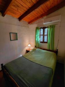 a bedroom with a green bed and a window at La Quebrada del Molle in San Marcos Sierras