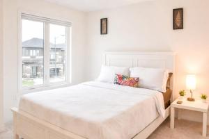 a white bedroom with a large bed and a window at Spacious 4BR Home with EV Charger in Cambridge