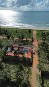 a house on a beach with palm trees and the ocean at Recanto MARES DO SUL in Coruripe