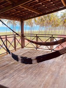 a hammock on a deck with a view of the beach at Recanto MARES DO SUL in Coruripe +6 photos