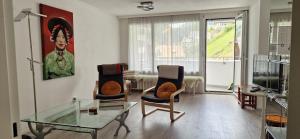 a living room with a glass table and two chairs at Tolle zentrale Wohnung in Engelberg