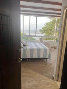 a bedroom with a bed and a large window at Puerto Beach House in Puerto Colombia +2 photos
