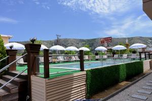 ein Pool mit Tischtennisplatten und weißen Sonnenschirmen in der Unterkunft Max Kriti Hotel in Shëngjin