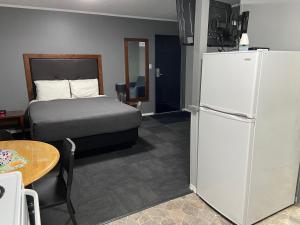 a bedroom with a bed and a refrigerator and a table at Monashee Lodge in Revelstoke