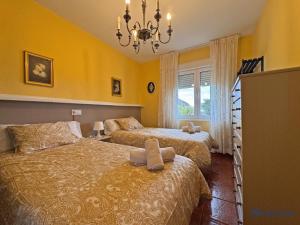 a bedroom with two beds and a chandelier at Apartamento Barro Playa in Barro de Llanes