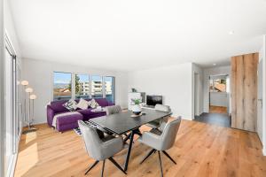 a living room with a table and a purple couch at Penthouse Exclusif - Grande Terrasse - Avenches - Self Check-in in Avenches +4 photos