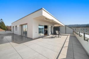 a white house with a large deck with chairs at Penthouse Exclusif - Grande Terrasse - Avenches - Self Check-in in Avenches