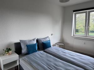 a bedroom with a bed with blue pillows and a window at CityZen Apartment CpH in Copenhagen