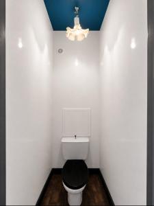 a white bathroom with a toilet and a chandelier at Apparte 104 avec Jacuzzi in Cap d'Agde