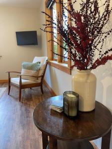 a living room with a table and a vase with flowers at 1860 Lawrence Cottage in Lawrence