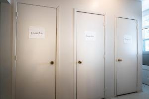 three white doors with signs on them in a room at Camp Val Notre-Dame in Herouxville