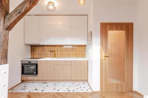 a kitchen with white cabinets and a wooden door at Podkrovní Apartmán in Třebíč