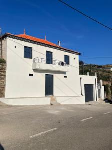 a white building with a balcony on the side of it at Casa dos Bardos in Alvações do Corgo