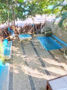 a swimming pool with two blue benches and trees at Two-Bedroom Apartment with Ocean View in La Ciénaga