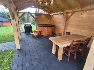 a wooden patio with a wooden table and a tub at Roztoczańska Kryjówka in AdamÃ³w